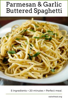 a white bowl filled with pasta and parmesan garlic buttered spaghetti on top of a wooden table