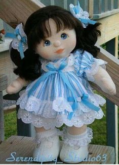 a small doll with black hair and blue eyes is sitting on a wooden porch railing