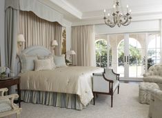 a bedroom with a bed, chair and chandelier next to a patio door