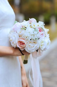 a woman holding a bouquet of white and pink flowers