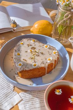 a cake sitting on top of a plate next to a cup of tea and flowers