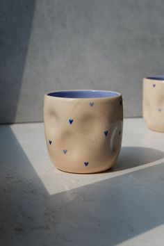 two ceramic cups with hearts painted on them