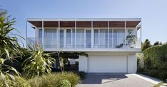 the house is surrounded by greenery and trees on both sides of the driveway area