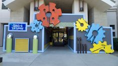 the entrance to an amusement park with colorful gears on it's walls and doors