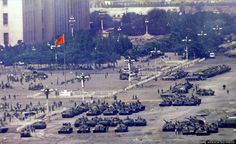 tanks are lined up in the middle of a parking lot with people standing around them