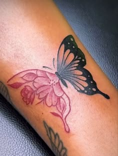 a butterfly tattoo on the foot of a woman's leg with pink and black flowers