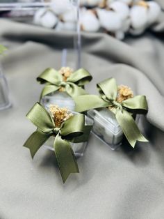 two small green bows sitting on top of a gray cloth covered table next to eggs