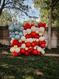 balloons are stacked on top of each other in front of a wooden fence and tree