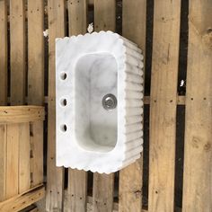 a white sink mounted to the side of a wooden wall next to wood planks