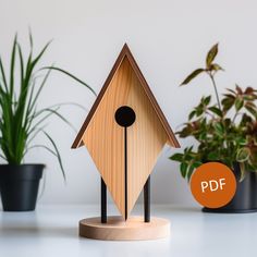 a wooden birdhouse sitting on top of a white table next to potted plants