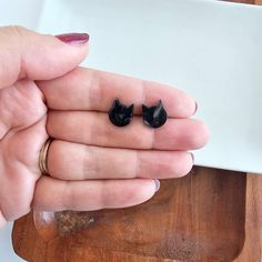 a woman's hand holding two small black cat ears