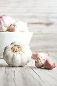 two white bowls filled with garlic on top of a wooden table