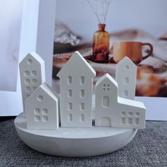 three white houses on a plate with a cup and saucer in the background