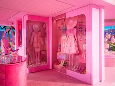 a pink room with two dolls in the closet and a mirror on the wall behind them