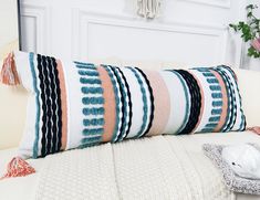 a white couch with a multicolored striped pillow on it's backrest