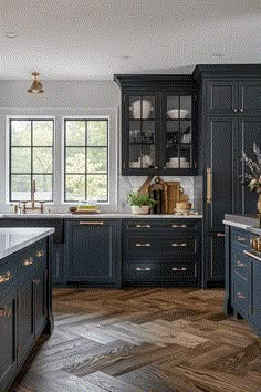 a kitchen with dark blue cabinets and gold handles on the countertops, along with wooden flooring