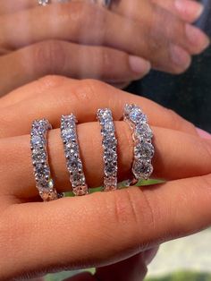 a woman's hand holding three diamond rings