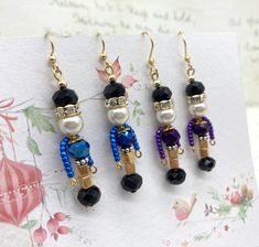 three pairs of earrings with beads and pearls on them sitting on top of a piece of paper