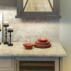 a kitchen counter with dishes and wine glasses on it