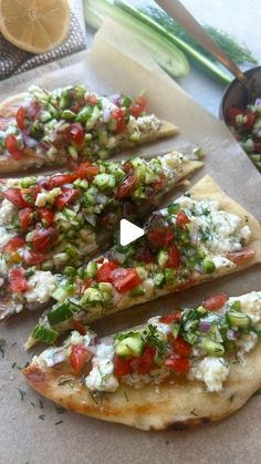 several flat bread pizzas with tomatoes, cucumbers and other toppings on them