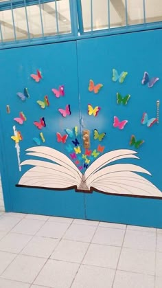 an open book with butterflies on it sitting in front of a blue wall next to a white tiled floor