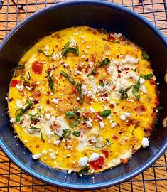 an omelet with spinach and cheese in a blue bowl on a table