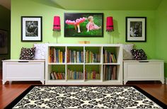 a living room with green walls and black and white rugs on the hardwood floor