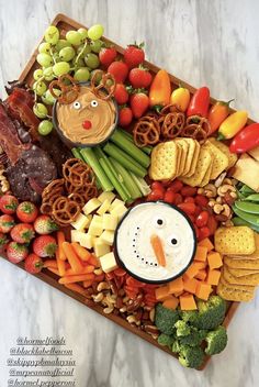 a platter filled with fruit, vegetables and crackers for a christmas themed snack