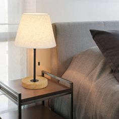 a lamp sitting on top of a wooden table next to a gray couch in a living room