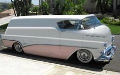 a white and pink car parked in front of a house