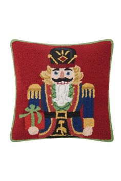 a red pillow with a nutcracker design on the front and green trimmings