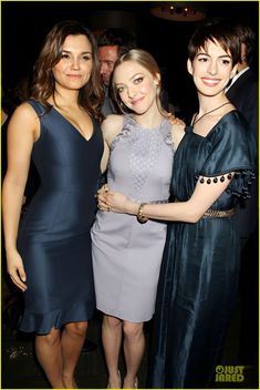 three women standing next to each other at an event