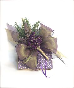 a purple and gold boutonniere with greenery on it's side