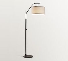 a floor lamp with a white shade on the top, and a black metal base