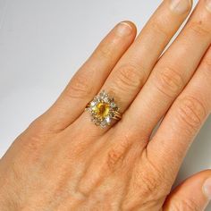 a woman's hand with a yellow and white diamond ring on top of it