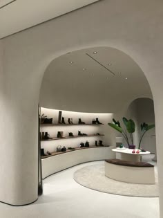 the inside of a shoe store with lots of shoes on shelves and plants in vases