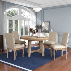 a dining room table with four chairs and a blue area rug on the wooden floor