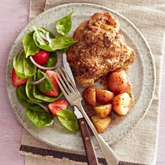 a white plate topped with meat and potatoes next to a salad on top of a table