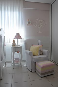 a baby's room with a white chair, pink and yellow decor and a tree on the wall