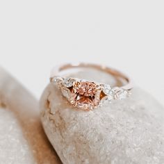 a pink diamond ring sitting on top of a rock