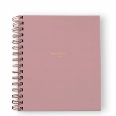 a pink notebook with the words daily planner written in gold foil on it, sitting open