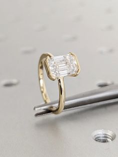 a diamond ring sitting on top of a piece of metal next to a nail pin