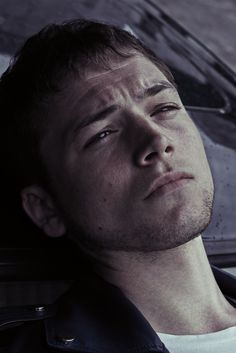 a man sitting in the back seat of a car looking off into the distance with his eyes closed