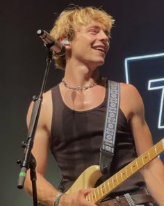 a man that is standing in front of a microphone with a guitar on his chest