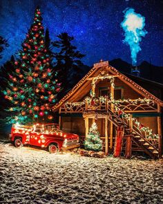 a red truck parked in front of a christmas tree with lights on it and a lit up fire hydrant