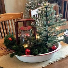 a small christmas tree in a bowl with lights and ornaments on the table next to it