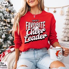 Santa's favorite Cheerleader, cute retro style cheer Christmas sweatshirt for cheerleaders. This cheerleading holiday sweatshirt has a unisex fit. Please see the size chart and fit guide in the listing photos. 💗 Please note there are slight print color variations depending on chosen sweater color STYLE GUIDE *Soft and comfy unisex crewneck sweatshirt *Set in sleeves *Loose fitting style *No side seams MATERIAL *50% cotton/50% polyester 👉 SIZE GUIDE You can find the size guide in the listing photos including measurements. Please check these before purchase and if in doubt, compare to one of your own comfortable fitting garments so you can be sure to order the correct size. If you are unsure as to what size to order then please get in touch to discuss your requirements prior to purchase, w Christmas Fan Merchandise Crew Neck Tops, Winter Long Sleeve Tops For Cheerleading, Winter Crew Neck Sweatshirt For Cheerleading, Holiday Sweatshirts, Xmas Jumpers, Holiday Sweatshirt, Funny Christmas Shirts, Sweatshirt Set, Funny Christmas