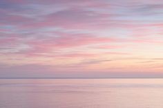 the sky is pink and purple as it reflects in the water