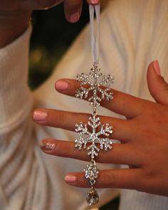 a woman's hand holding a snowflake ornament