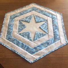 a blue and white quilted table topper with a star on it's center